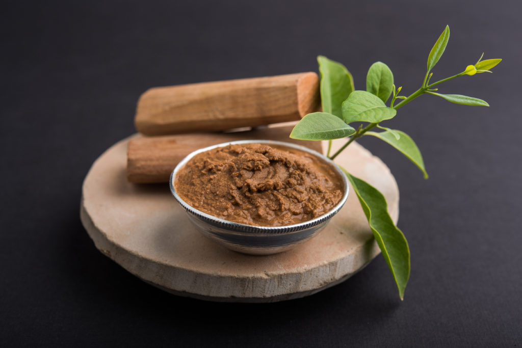 Ayurvedic Chandan powder or sandalwood paste in silver bowl with sticks
