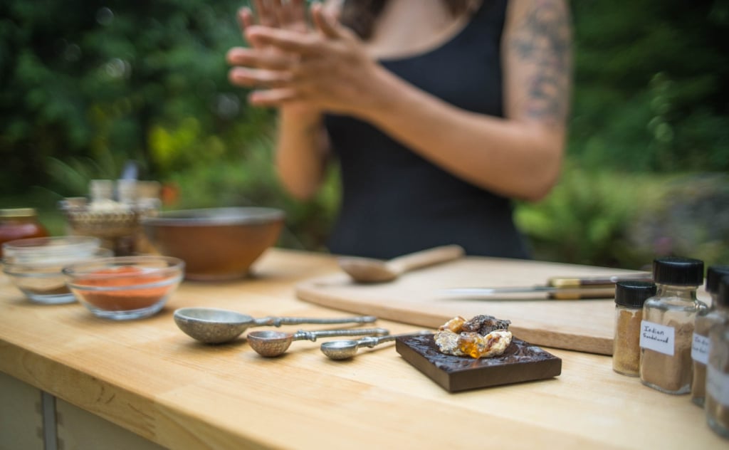 CraftingTable copy.jpg 01312022 copy woman standing over crafting table covered in incense ingredients and incense making tools