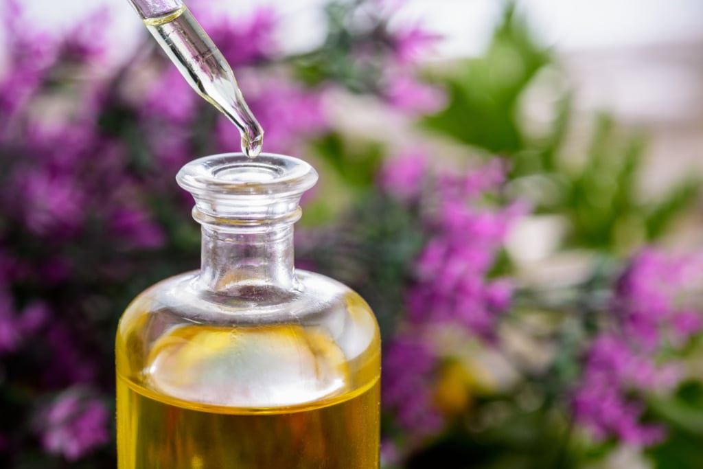 Diluting essential oil pipette dropping drops of essential oil into a big bottle of carrier oil