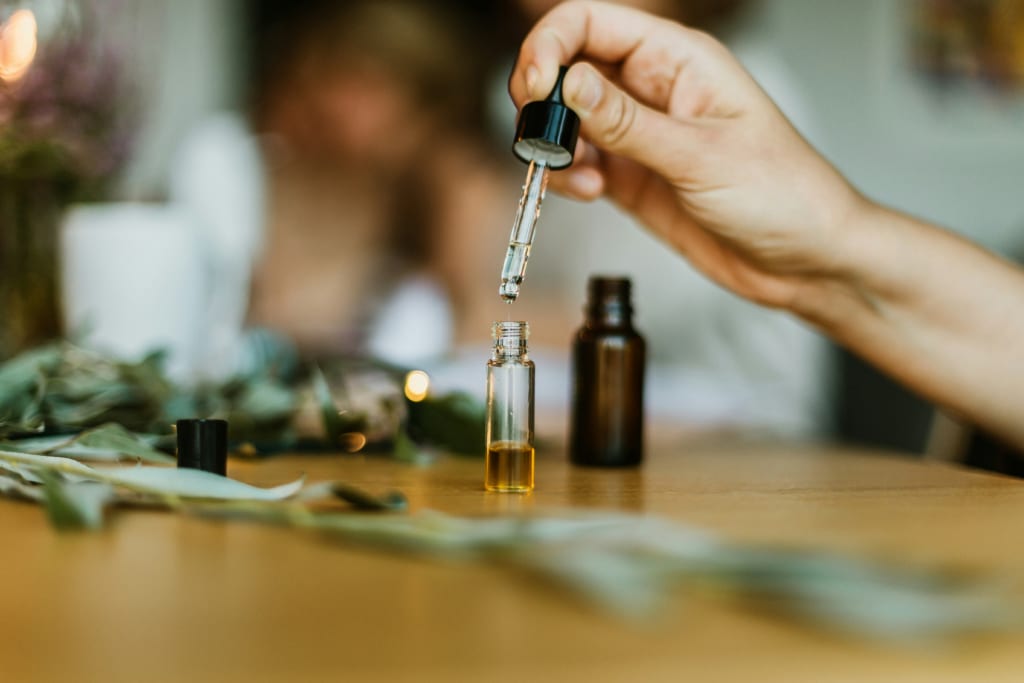 perfume oil dropper unsplash.jpg 11_10_2024 copy hand holding dropper vial dropping essential oils into small clear glass tincture bottle