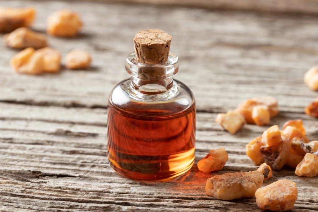 glass cork bottle of benzoin oil next to benzoin resin on a counter