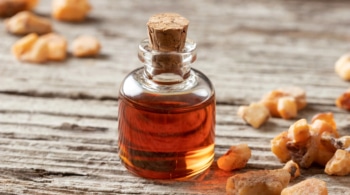 glass cork bottle of benzoin oil next to benzoin resin on a counter