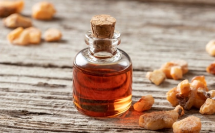 glass cork bottle of benzoin oil next to benzoin resin on a counter