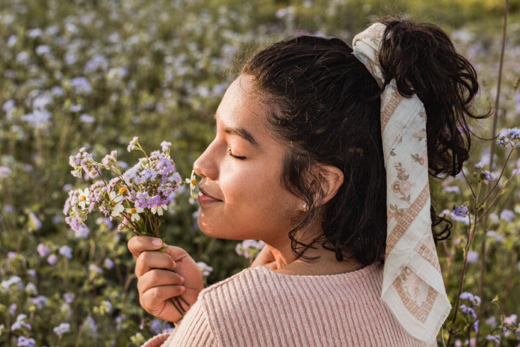 bouquet-edited-marcela-miranda-unsplash.jpg 01232022 copy young woman smelling a bouquet of fresh flowers standing in a field in nature
