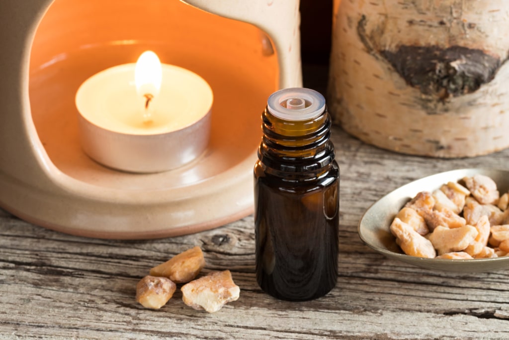 benzoin essential oil sitting on a table next to benzoin resin and a candle essential oil diffuser