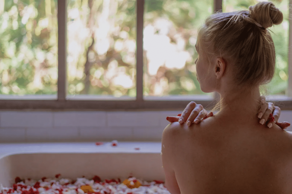 women in an herbal bath filled with rose petals