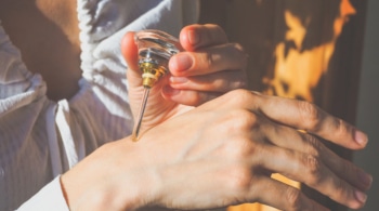Person applying oil attar natural perfume to back of hand