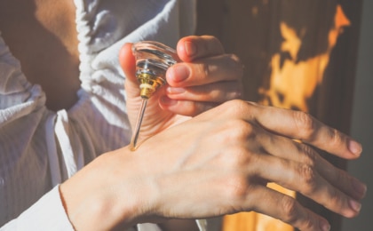 Person applying oil attar natural perfume to back of hand