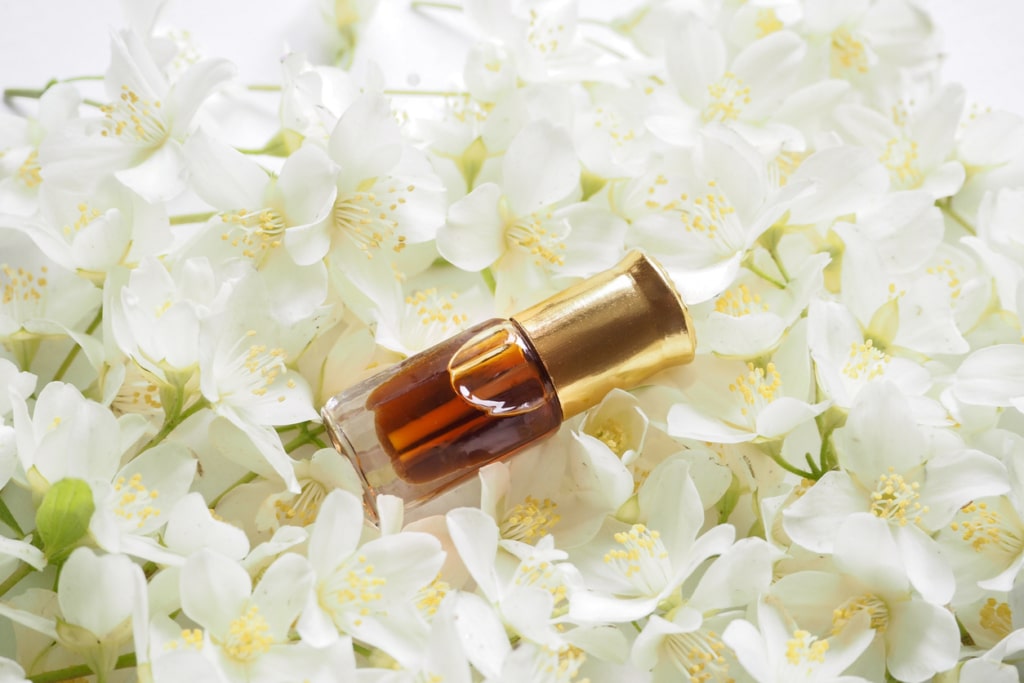 bottle of attar natural perfume on jasmine flowers