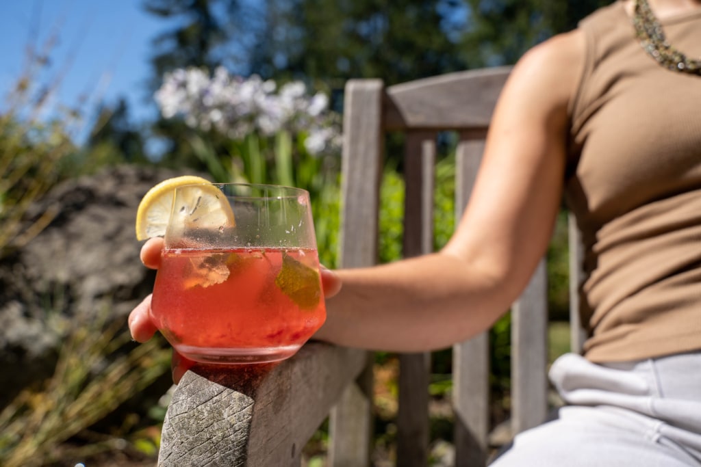 Woman holding herbal mocktail glass sitting outside